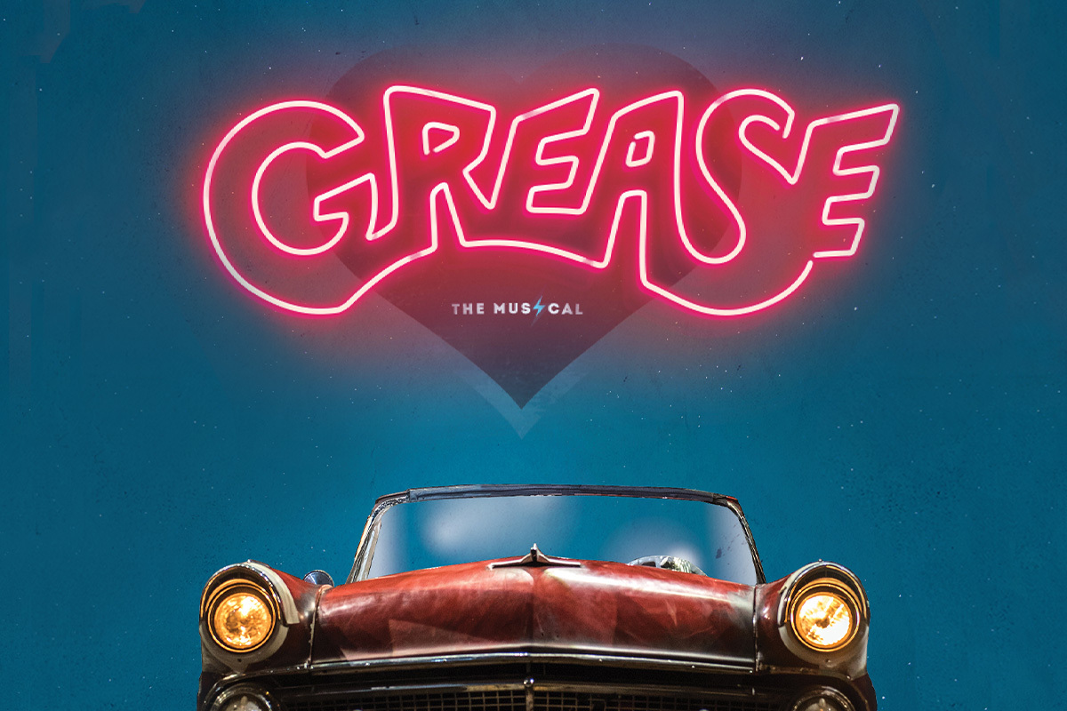 This promotional image for Grease features the title in bold, white letters against a sparkling, bokeh background. The backdrop transitions from warm golden tones at the top to cool blues at the bottom, creating a fun and lively atmosphere. The glowi