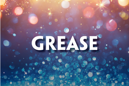 This promotional image for Grease features the title in bold, white letters against a sparkling, bokeh background. The backdrop transitions from warm golden tones at the top to cool blues at the bottom, creating a fun and lively atmosphere. The glowi