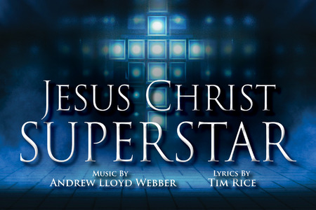 The promotional image for Jesus Christ Superstar features the title in bold, white letters against a sparkling, bokeh background. The backdrop transitions from brightly illuminating a cross outline in the center to shadow and smoke in the perimeter